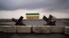 Barreras antitanque yacen frente a una casa pintada con los colores de la bandera ucraniana en las afueras de Kiev, Ucrania. (AP Foto/Rodrigo Abd)
