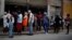 Cubanos hace fila para comprar pollo en una tienda subsidiada o "bodega" en La Habana. 