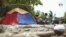 En un improvisado campamento en la playa, pasan los dias y noches algunos migrantes venezolanos, quienes cocinan y lavan su ropa en el mar. Foto: VOA.