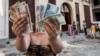 Una mujer muestra pesos cubanos CUP y pesos convertibles (CUC).