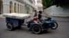 Una familia transporta un colchón en una motocicleta por las calles de La Habana. 