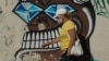 Mujer con máscara camina frente a mural alegórico a COVID-19 en Cuba