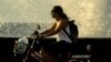 Una mujer se traslada en bicicleta por el Malecón habanero en medio de la pandemia de coronavirus. (AP/Ramon Espinosa)